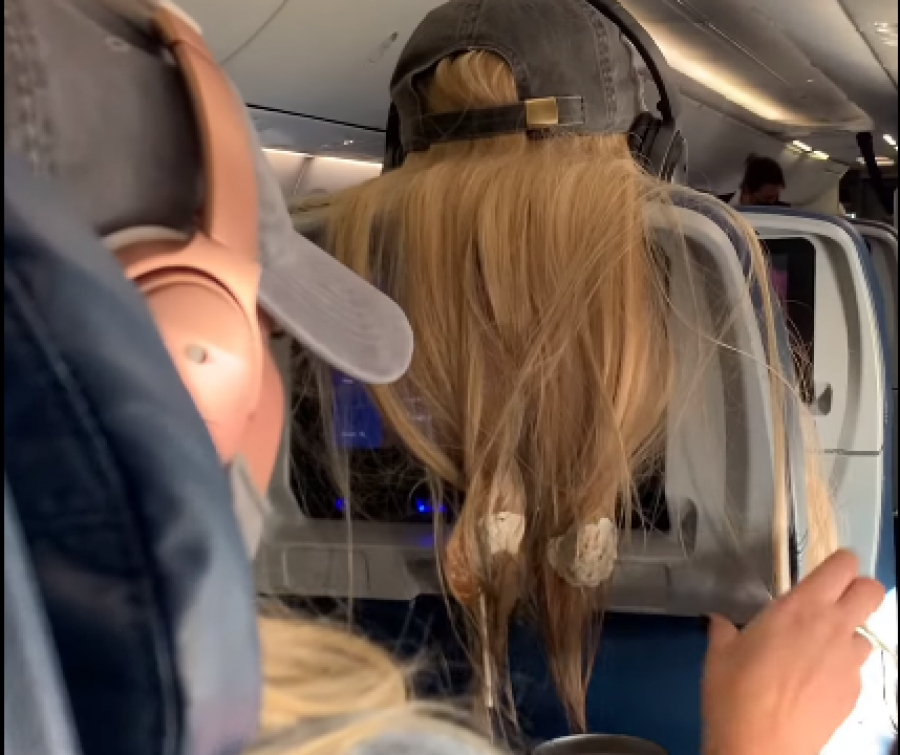Biondina hidhte flokët prapa ulëses në aeroplan, pasagjerja ia pret ato dhe ia lidh me çamçakëz