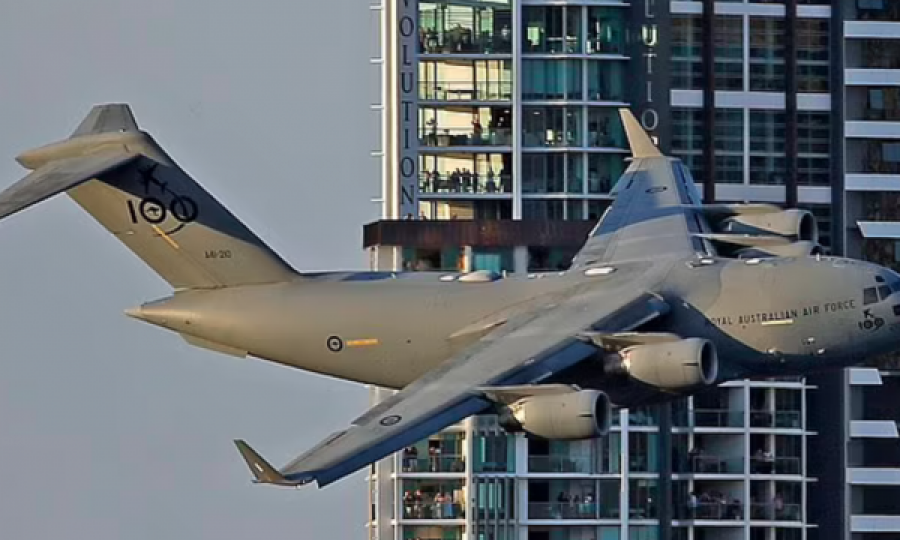Aeroplani i madh ushtarak futet mes ndërtesave nëpër qytet 