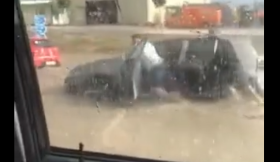 Qytetari duke shtyrë veturën mes ujit nga stuhia që goditi Prishtinën