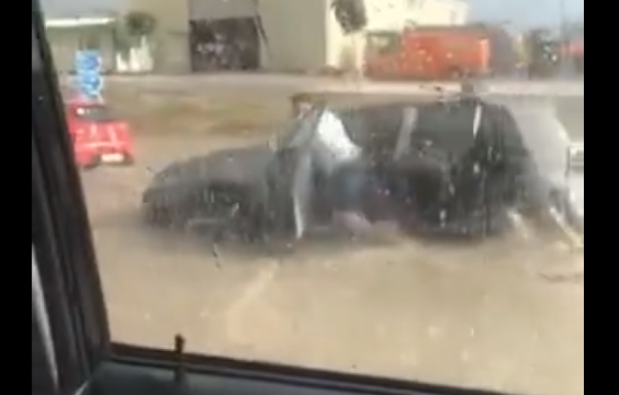 Qytetari duke shtyrë veturën mes ujit nga stuhia që goditi Prishtinën